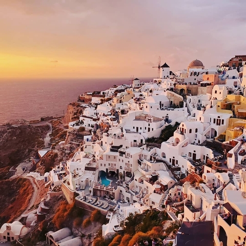 Aerial view of Santorini with white buildings at sunset.