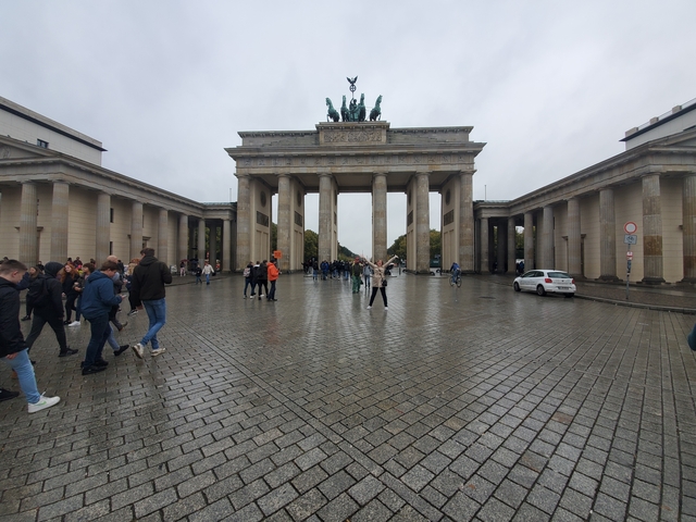       Brandenburg Gate with people walking on a rainy day.
  
