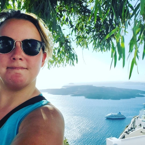 Woman posing with a scenic view of the sea and islands.