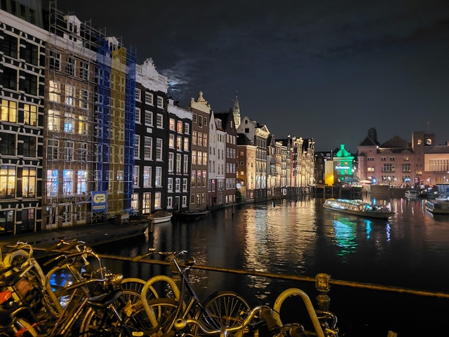 Night scene of Amsterdam with lit buildings and canal.