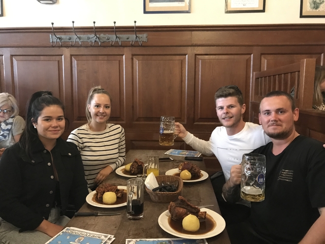       Group enjoying a meal with beer mugs in a wooden interior.
  