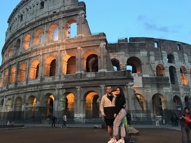       Couple in front of the Colosseum in Rome at twilight.
  