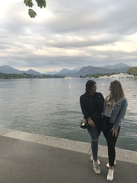       Two people by a lake with mountains in the background.
  