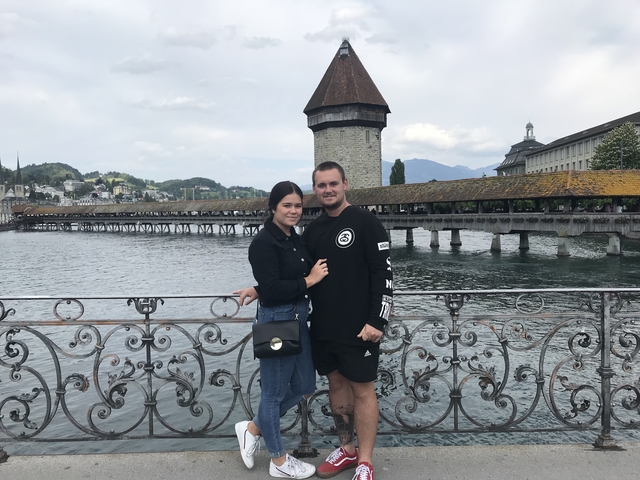       Couple posing on a bridge with mountains in the distance.
  