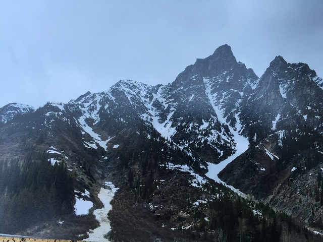 Mountains with patches of snow and coniferous trees.