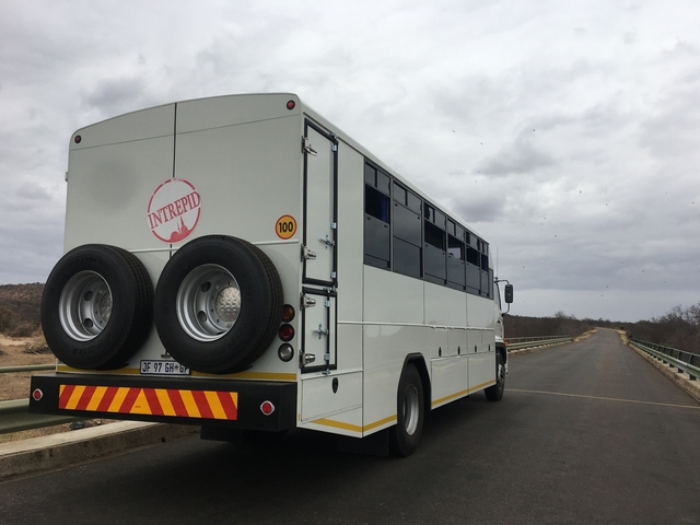Intrepid bus on a road with hilly landscape.