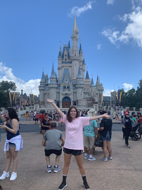 Person in front of a fairytale castle with a large crowd.