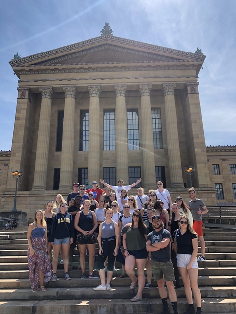 Large group of people posing on steps in front of a building with columns.