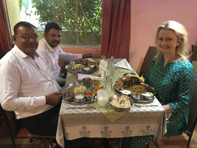       Three people enjoying a traditional Indian meal at a restaurant.
  