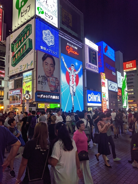 Crowd gathered under large digital billboards at night