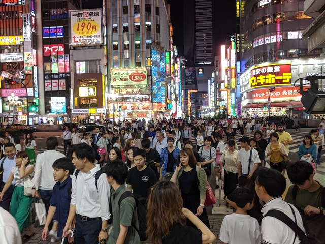 Busy intersection with many pedestrians and colorful signs