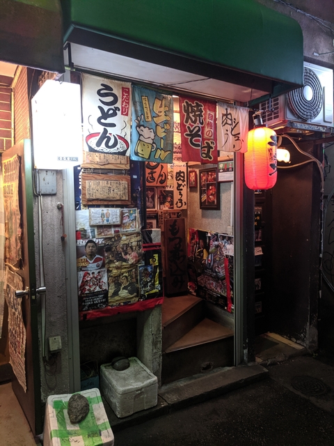       Entrance to a cozy Japanese restaurant with many posters
  