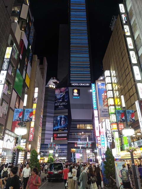       Skyscraper with Godzilla figure and bright signage
  