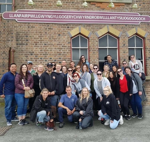 Large group of people posing in front of a brick building