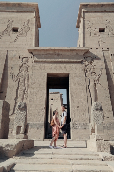 People standing in front of an ancient temple with relief carvings.