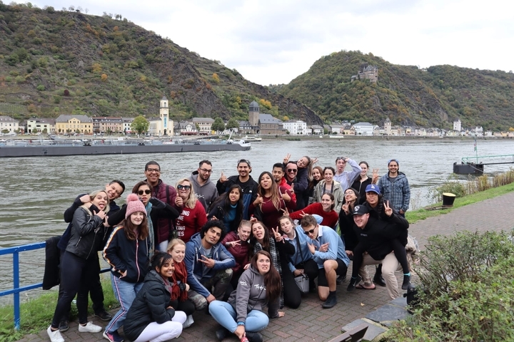 Energetic group photo by a river and hills.