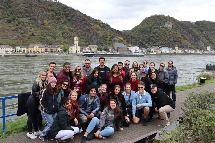 Large group photo by a river with scenic hills.