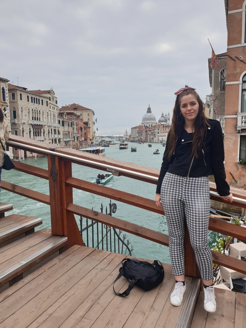 Person on a bridge over a canal in Venice with historical buildings.