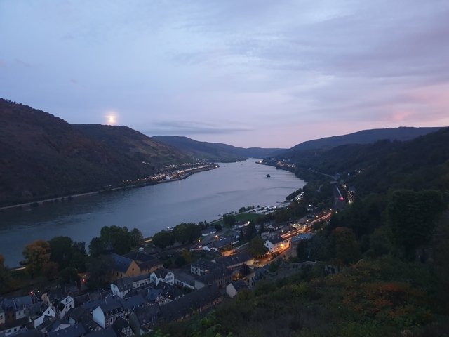 Scenic river view at dusk with lights and hills.