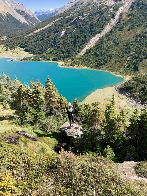 Person standing on a rock overlooking a lake.