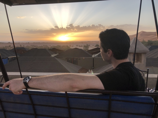       Person watching a sunrise over tents in the desert.
  
