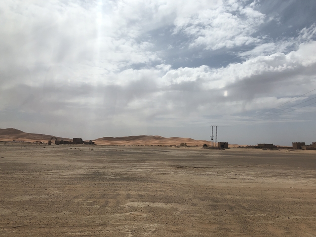       Desert landscape with distant buildings and power lines.
  