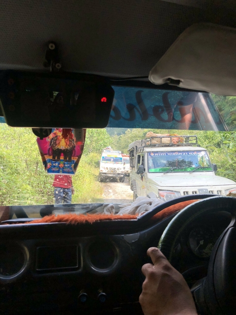 Vehicles on a narrow dirt road seen through a windshield.