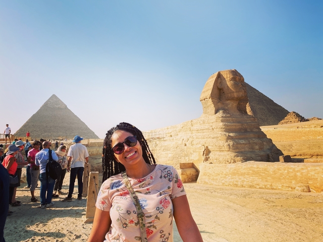       Smiling person with the Sphinx and a pyramid in the background.
  