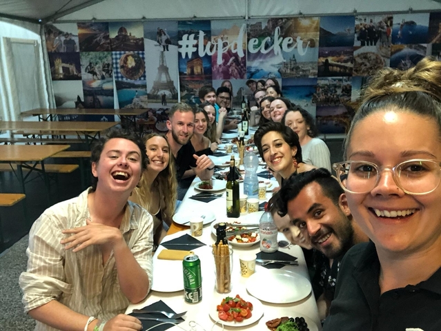 Group of friends at a table with food and drinks.