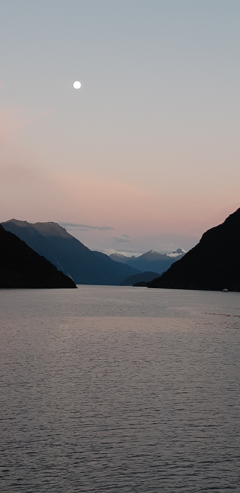Mountainous landscape image with a body of water at dawn.