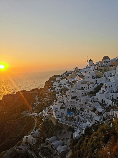       Santorini's white buildings at sunset with ocean view.
  