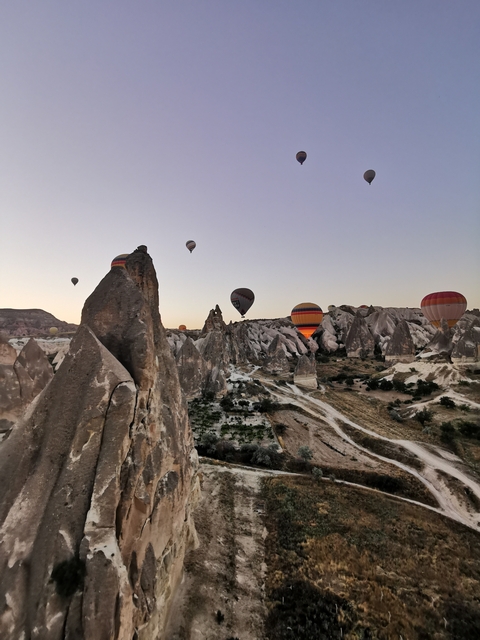 Hot air balloons floating over unique rock formations.