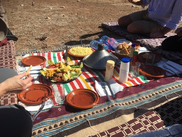 Picnic setup with Moroccan dishes on decorative mats.