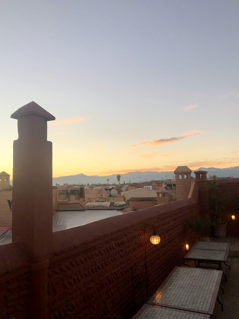       Sunset over city rooftops with mountains in the distance.
  