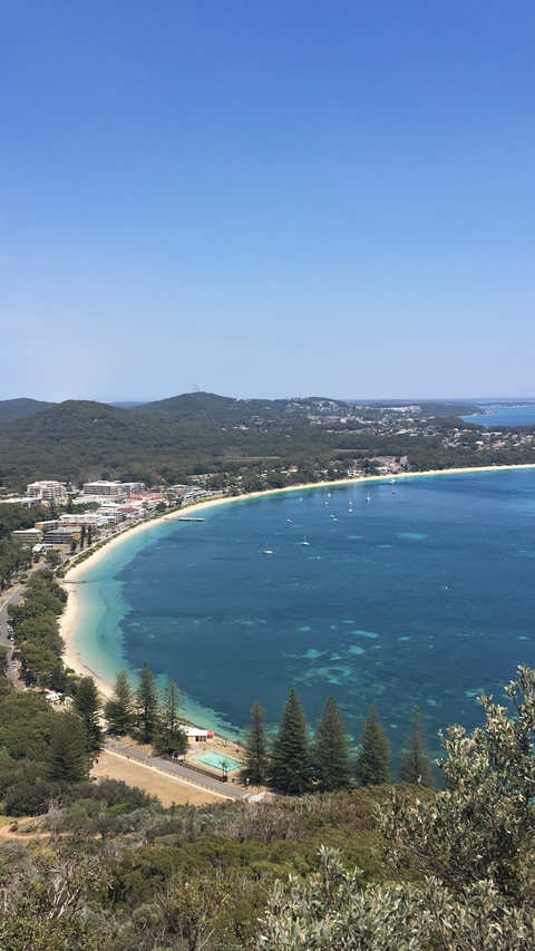       Aerial view of a coastal city with a beach lined with boats.
  