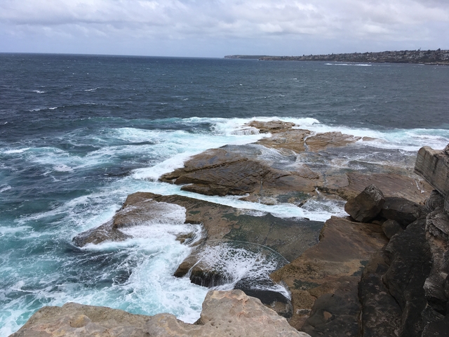       Rocky shoreline with waves crashing against it.
  