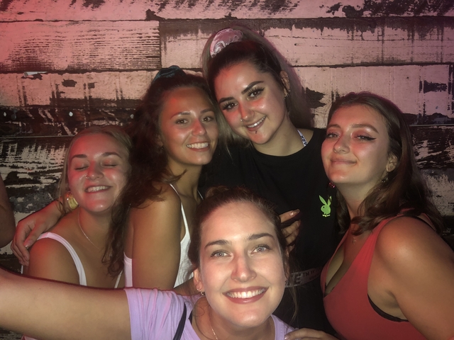 Group of young women posing closely in a nightlife setting.