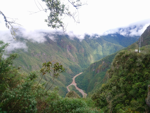 A scenic view of lush green mountains and a winding river under a cloudy sky.