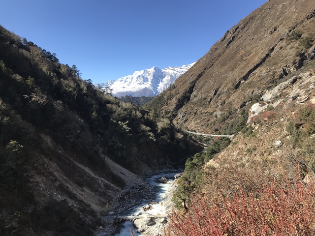 A mountain valley with a winding river and snowy peaks.