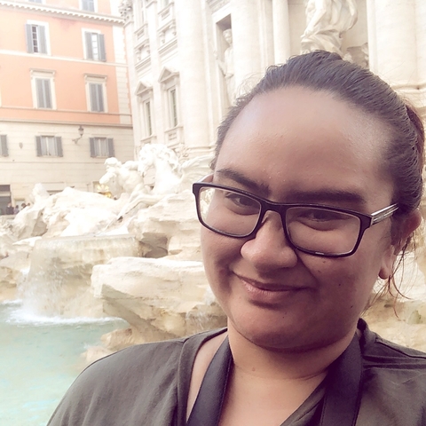 Person wearing glasses in front of a fountain.