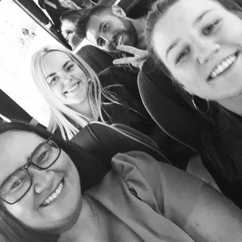 Black and white image of three people smiling indoors or in a vehicle.