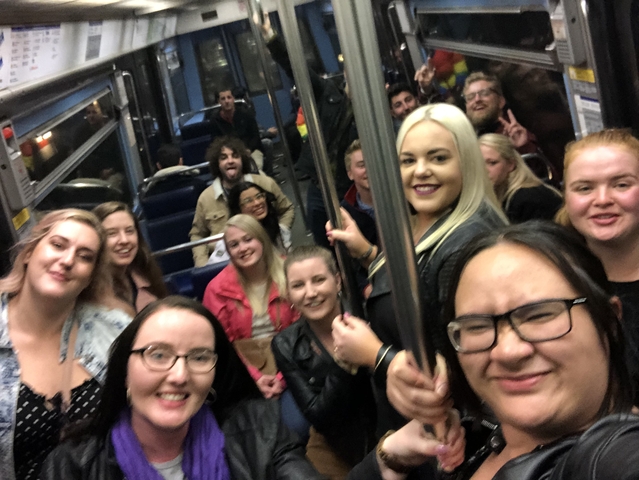 A group of people posing inside a bus or train with a crowded interior.