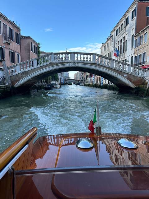       Boat navigating under a bridge in Venice.
  