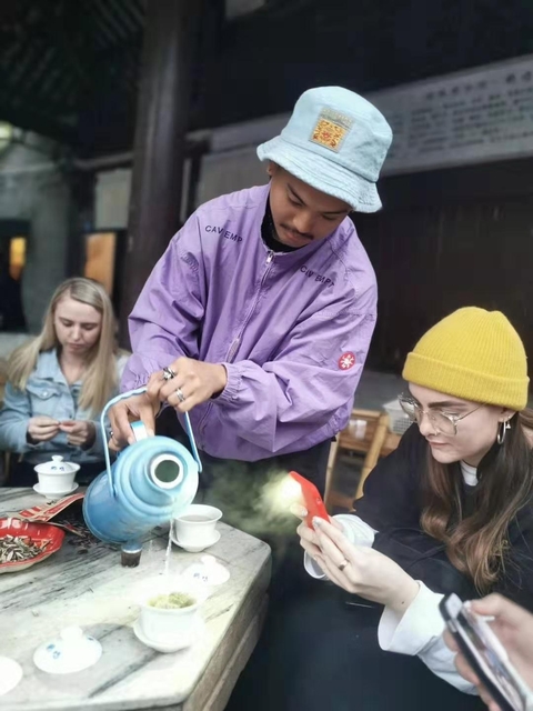A person pouring tea for others in a traditional setting.