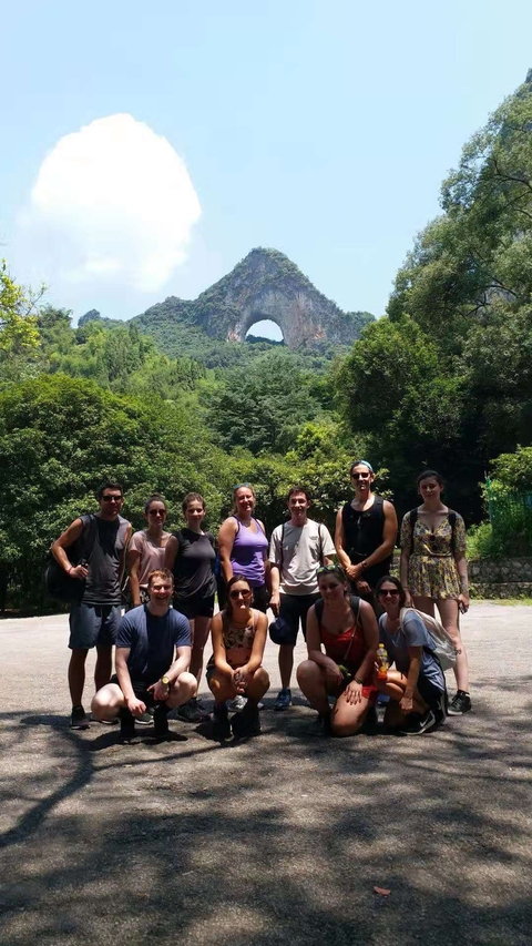 Group of people in a forested area with mountains.