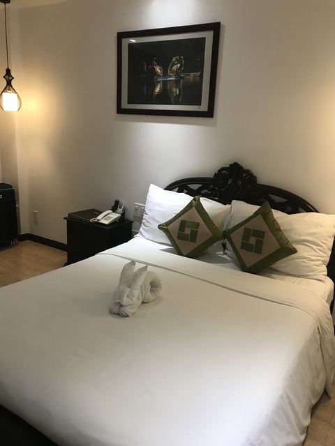 Hotel room with a neatly made bed and towels folded into swans.