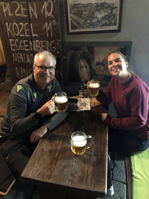 People having drinks at a wooden table.