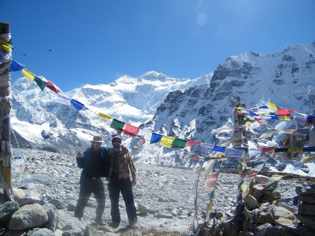 Group of hikers posing with Tibetan prayer flags and snow-capped mountains