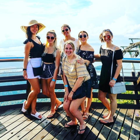 A group of women posing on a viewing platform with hills in the background.
