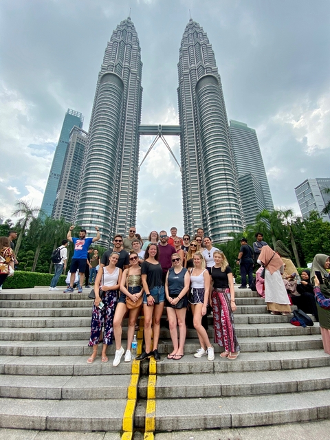 A group of people standing in front of the Petronas Towers.